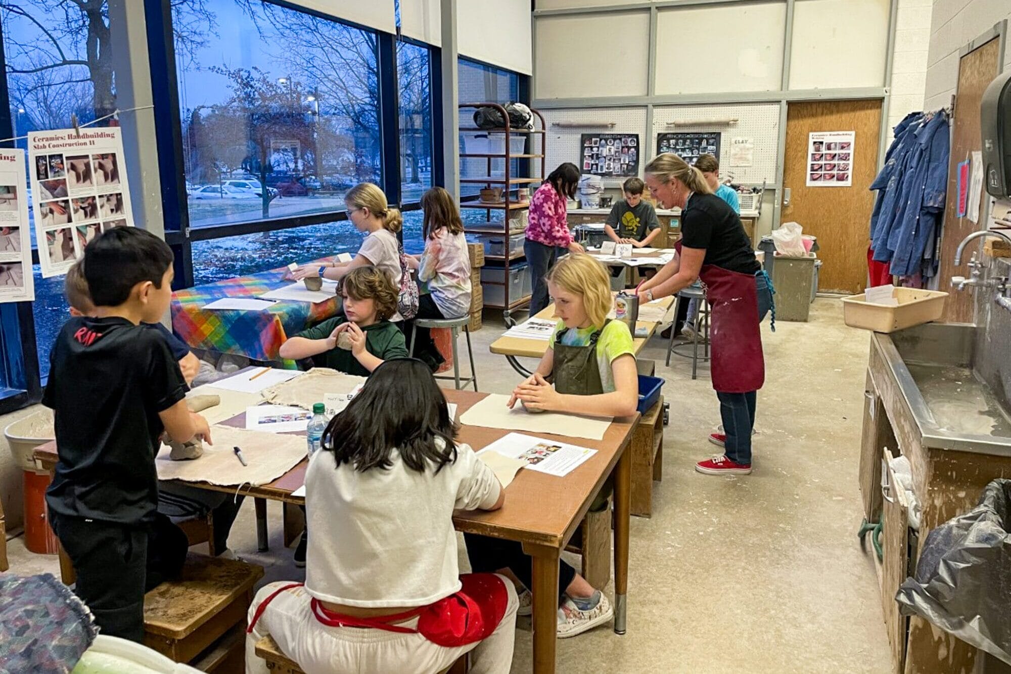a group of about 8 kids around the age of 10 in a classroom setting working with clay