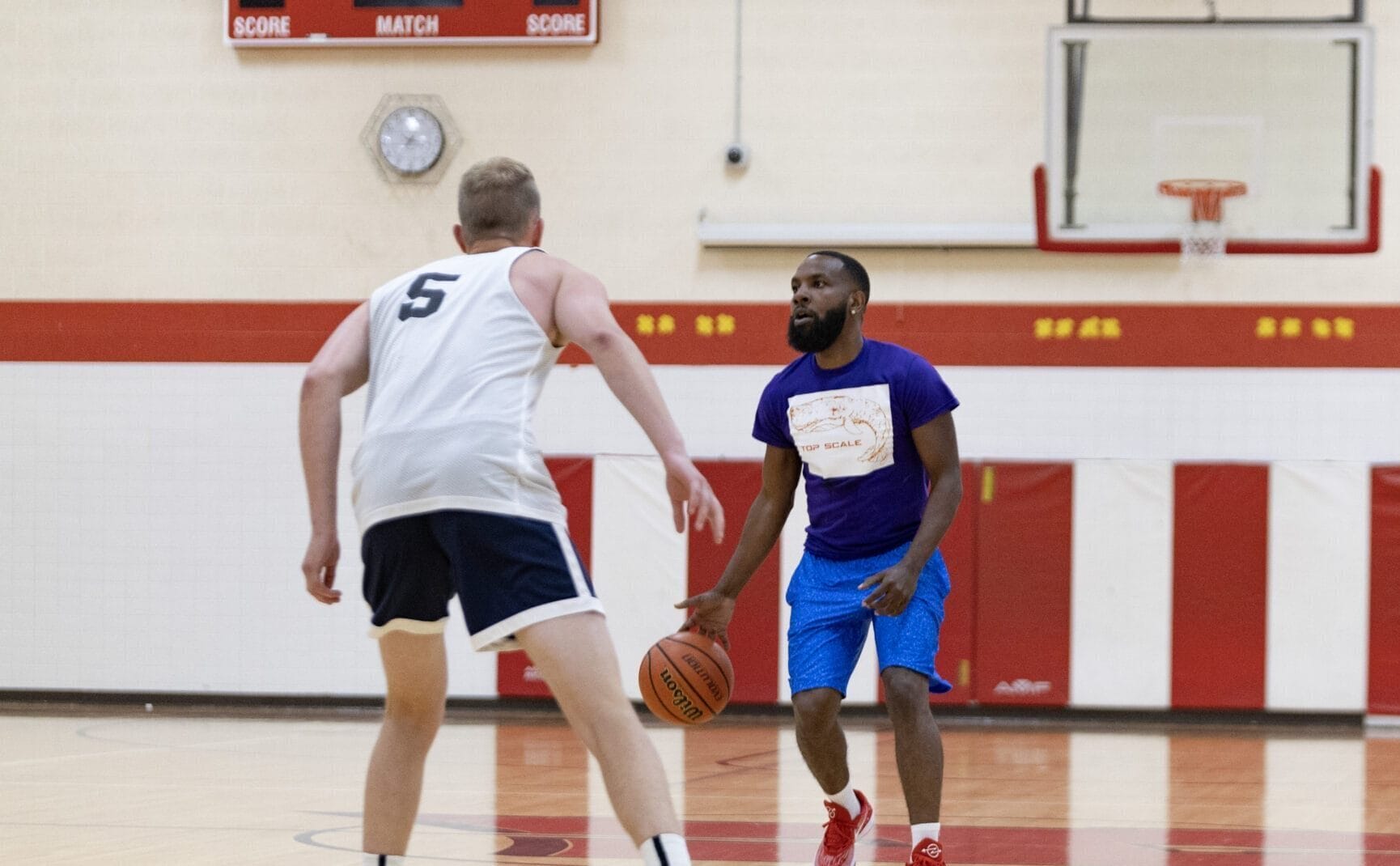 2 adults playing basketball together in a gymnasium