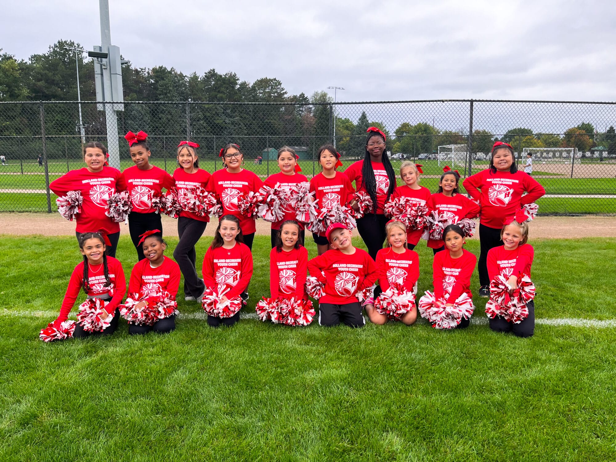 group of about 20 3rd - 5th grade cheerleaders in their uniforms posing for a group photo